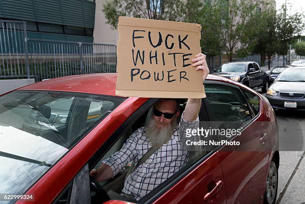 Motorist holds a sign while waiting for crowd of anti-Trump protesters to pass by in Los Angeles, California on November 12, 2016. According to the...