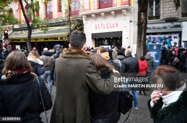 People stand in front of the Bataclan concert hall in Paris, on November 13 during a ceremony marking the first anniversary of the Paris terror...
