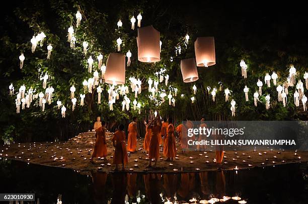 Novice Buddhist monks light lanterns for tourists to photograph at Wat Phan Tao temple to mark the beginning of the annual Yi Peng festival in the...