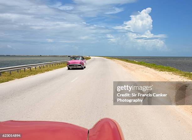 driver's pov of a vintage car on caribbean causeway leading to cayo santa maria, cuba - cayo santa maria stock pictures, royalty-free photos & images
