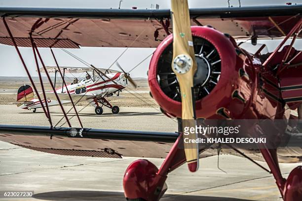 Picture taken on November 13, 2016 shows two German pilots Ingo and Bob sitting in their vintage Bü 131 Bücker Jungmann at an airfield in Cairo's 6th...