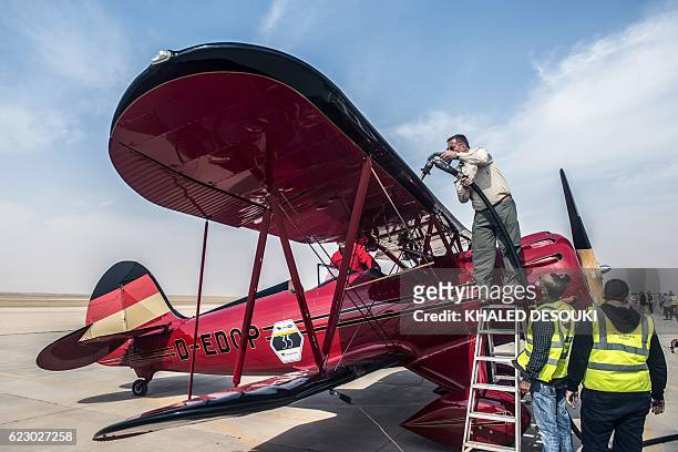 An official refuels the German team's Bü 131 Bücker Jungmann biplane at an airfield Cairo's 6th of October City, west of the Egyptian capital during...