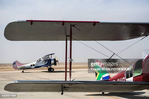 Picture taken on November 13, 2016 shows the Travel Air 4000 vintage biplane of the US team parked on the runway behind the South African DH82A Tiger...