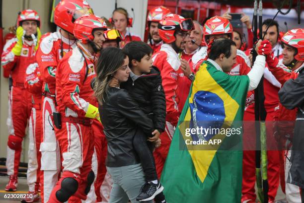 Tearful Williams Martini Racing's Brazilian driver Felipe Massa, wrapped in his country's flag, is followed by his wife and son as he is greeted by...