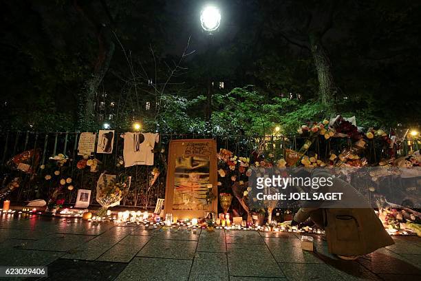 Man lights a candle at a makeshift memorial near the Bataclan concert hall in Paris on November 13, 2016 as France marked the first anniversary of...