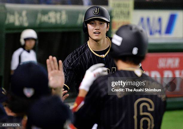 Designated hitter Shohei Ohtani of Japan celebrates with his team mates after scoring by the sacrifice fly by Infielder Hayato Sakamoto of Japan in...
