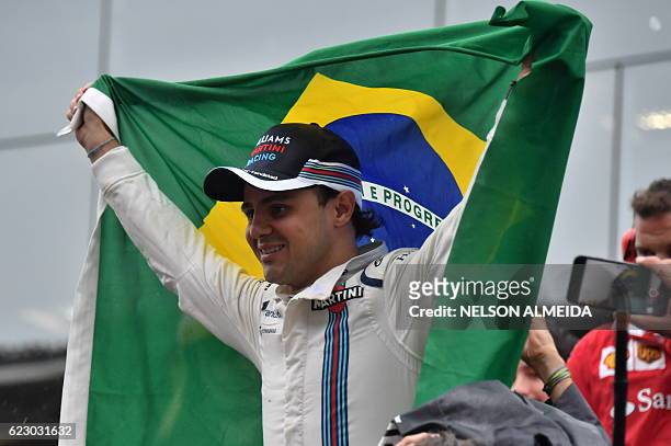 Williams Martini Racing's Brazilian driver Felipe Massa, holding his country's flag, greets fans after his final appearance at Interlagos circuit...