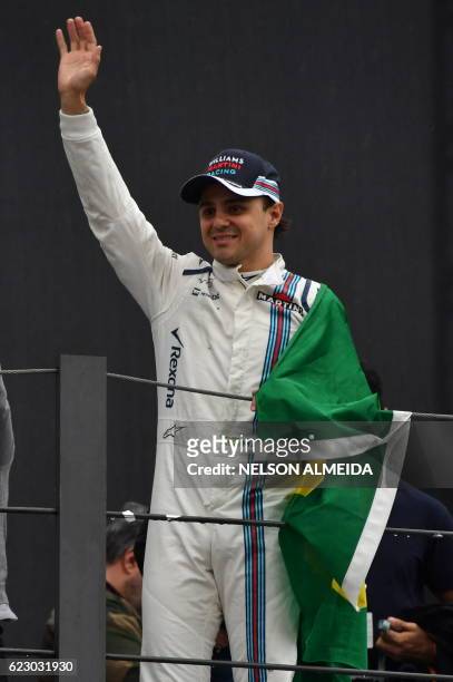 Williams Martini Racing's Brazilian driver Felipe Massa, holding his country's flag, greets fans after his final appearance at Interlagos circuit...