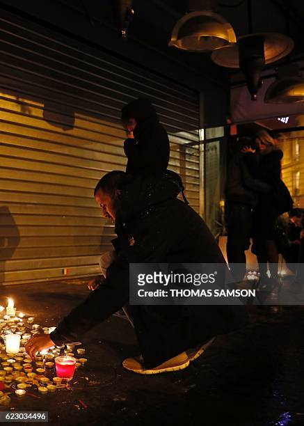 Man lights a candle at a makeshift memorial at Le Belle Equipe restaurant in Paris on November 13, 2016 to commemorate the one year anniversary of...