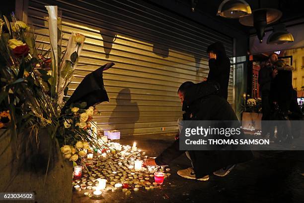 Man lights a candle at a makeshift memorial at Le Belle Equipe restaurant in Paris on November 13, 2016 to commemorate the one year anniversary of...