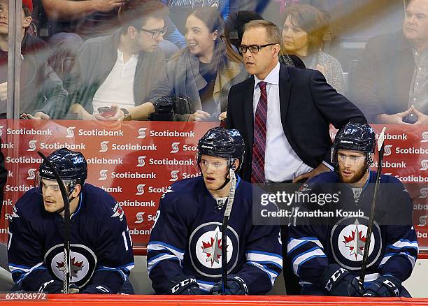 Head Coach Paul Maurice, Adam Lowry, Andrew Copp and Quinton Howden of the Winnipeg Jets look on from the bench during first period action against...