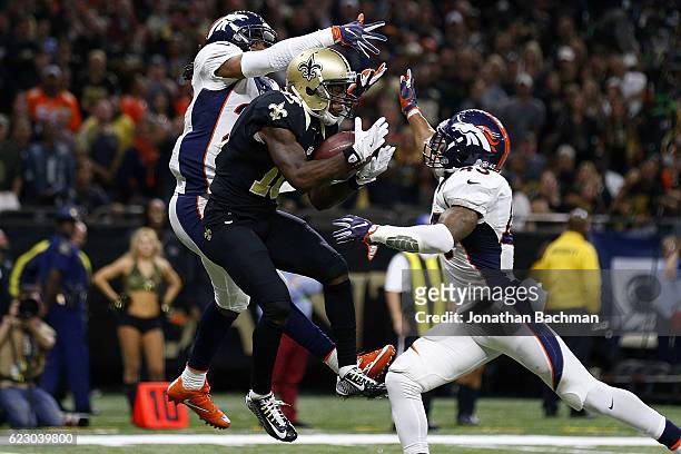 Brandin Cooks of the New Orleans Saints catches a touchdown over T.J. Ward of the Denver Broncos and Bradley Roby during the second half of a game at...