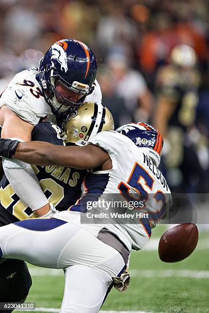 Michael Thomas of the New Orleans Saints fumbles the ball after being hit by Jared Crick and Corey Nelson of the Denver Broncos at Mercedes-Benz...