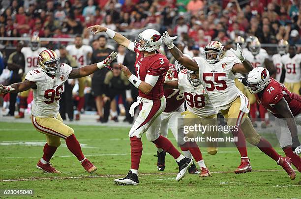 Carson Palmer of the Arizona Cardinals throws the ball down field just before getting hit by Ahmad Brooks and DeForest Buckner of the San Francisco...