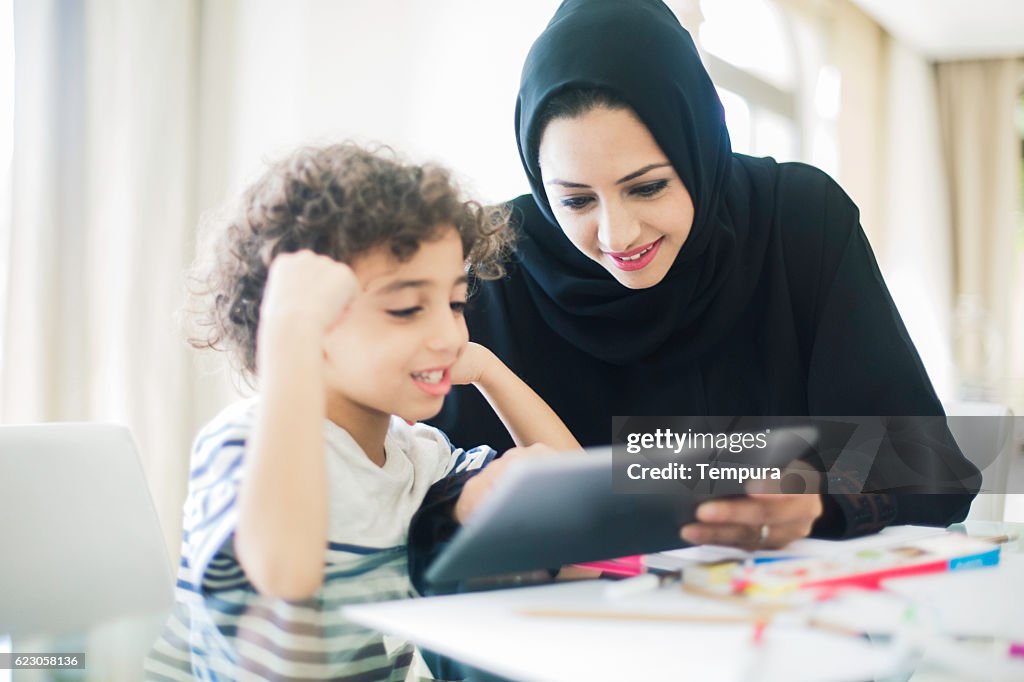 Middle eastern mother helping her child with homework.