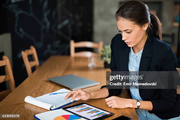 young businesswoman using digital tablet and analyzing business report. - 財政報告 個照片及圖片檔