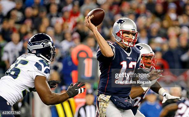 Tom Brady of the New England Patriots is hit by Cliff Avril of the Seattle Seahawks as he passes during the second quarter of a game at Gillette...