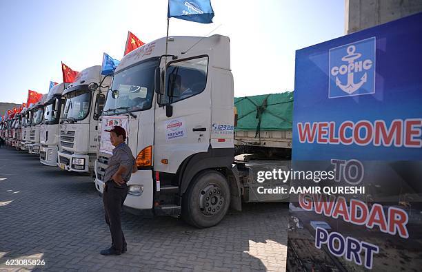 Chinese worker stands near trucks carrying goods during the opening of a trade project in Gwadar port, some 700 kms west of the Pakistani city of...
