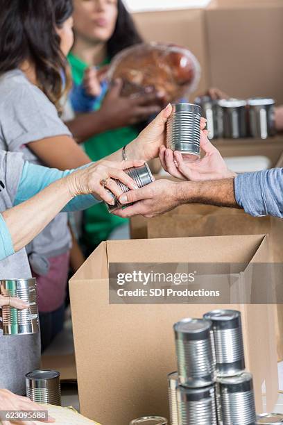 man donates canned goods at food bank - food donation stock pictures, royalty-free photos & images