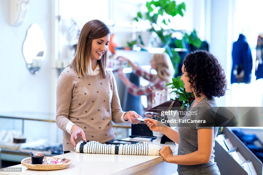 Ethnic female handing payment card over to female business owner