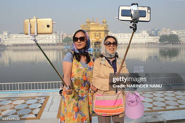 Chinese tourists take a 'selfie' at the Golden Temple in Amritsar on November 14 as Sikh devotees mark the 547th birth anniversary of Sri Guru Nanak...
