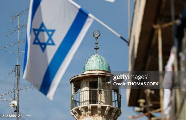 An Israeli flag waves in front of the minaret of a mosque in the Arab quarter of Jerusalem's Old City on November 14, 2016. - Israeli Prime Minister...