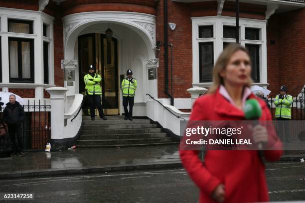 Police secure the doorway as a broadcast journalist reports from outside the Ecuadorian Embassy in London on November 14, 2016 where WikiLeaks...