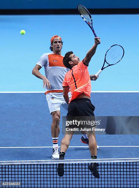 Feliciano Lopez of Spain watches on as Marc Lopez of Spain returns the ball during the mens doubles match against Henri Kontinen of Finland and John...