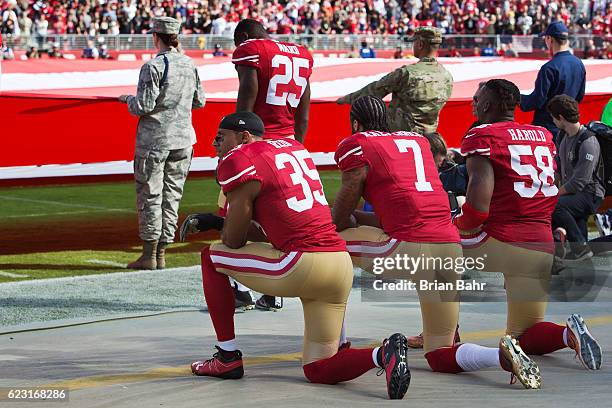 Quarterback Colin Kaepernick, safety Eric Reid, and linebacker Eli Harold of the San Francisco 49ers kneel before a game against the New Orleans...