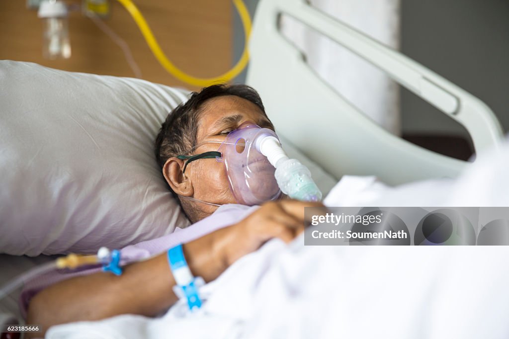 Anciana con máscara de ventilador en la cama del hospital