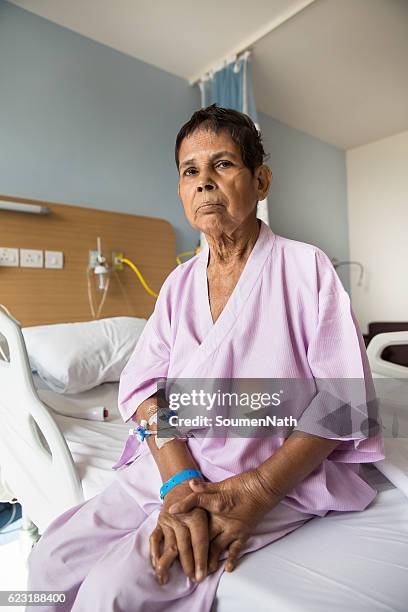 alte frau patient sitzt auf einem krankenhausbett - soumen nath soumennath stock-fotos und bilder