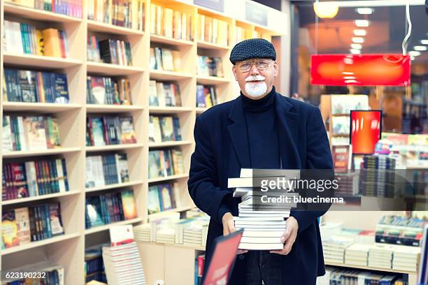 man with pile of book in bookstore - bookshop stock pictures, royalty-free photos & images
