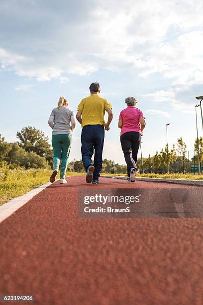 rückansicht eines eine gruppe von menschen joggen sie auf der laufstrecke. - 3 old men jogging stock-fotos und bilder