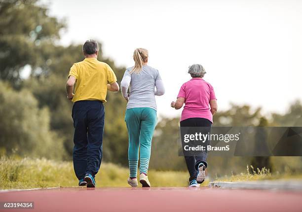 rückblick auf senioren, die auf einer sportbahn laufen. - 3 old men jogging stock-fotos und bilder