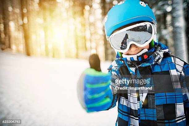 kleiner junge beim skifahren im verschneiten wald am sonnigen wintertag - wintersport stock-fotos und bilder
