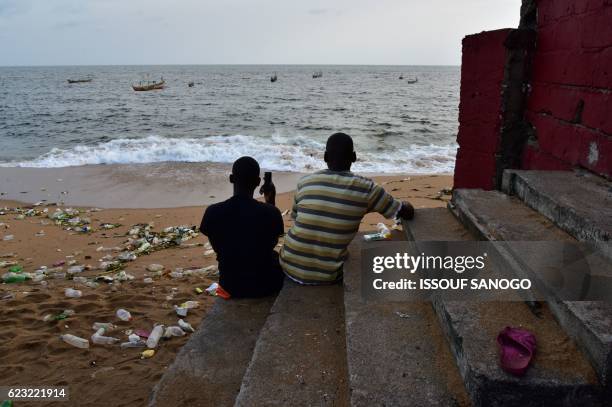 Men rest on the ruins of a hotel which was destroyed by the rise in the water level on November 14, 2016 on the beach in Vridi, the industrial...