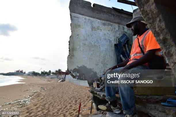 Man sits in the ruins of a hotel which was destroyed by the rise in the water level on November 14, 2016 on the beach in Vridi, the industrial...