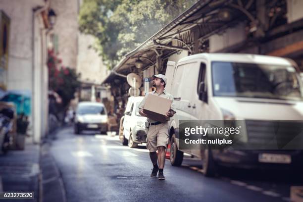 Messenger delivering parcel, walking in street next to his van