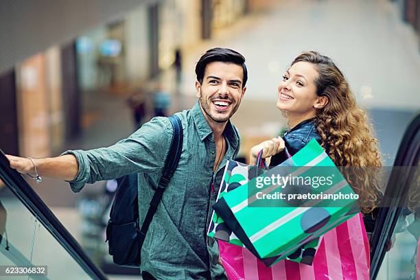 shopping couple are laughing on the escalator in mall - couple shopping in shopping mall stockfoto's en -beelden