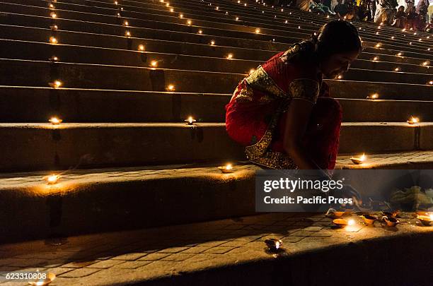 Devotee woman lights her earthenware lamps during the dev dipawali festival. Dev Dipawali is one of the famous festivals of Hindu which is celebrated...