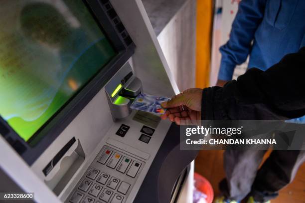 An Indian man inserts his card to withdraw money from a mobile bank ATM machine in New Delhi on November 15, 2016. - India is to use indelible ink to...