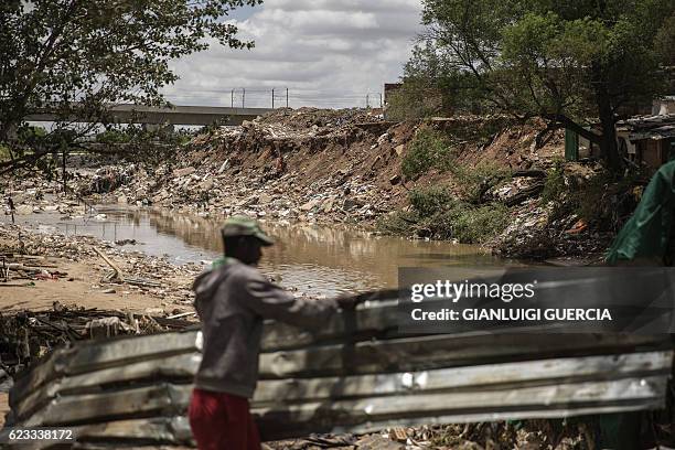 Man collects corrugated iron on the bank of a water stream in Alexandra Township, an area affected by the recents floods, on November 15, 2016 in...