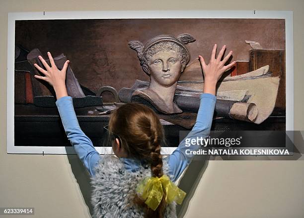 Visitor touches a painting created using a relief printing technique that adds volume and texture, a copy of "Still Life with the Attributes of the...