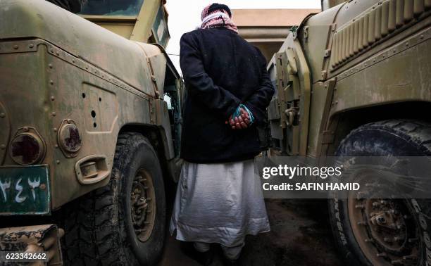 Suspected Islamic State group jihadist walks between two vehicles after his capture by Iraqi forces near the ancient town of Nimrud, located 30...