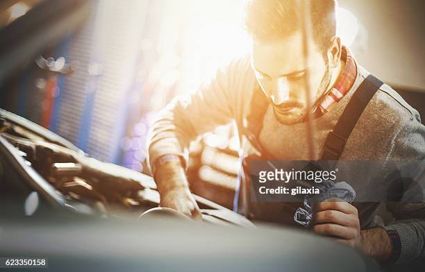 kfz-mechaniker inspiziert motor während des service-verfahrens. - autowerkstatt gegenlicht stock-fotos und bilder