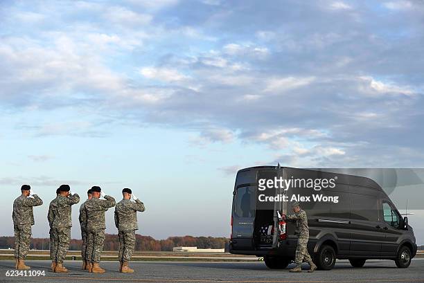 Members of a U.S. Army carry team salute as Air Force Senior Airman Brandon Norton closes the back doors of a transfer vehicle that carries the...