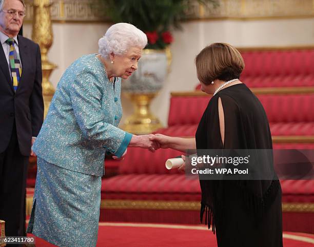 The High Commissioner for Belize, Her Excellency Ms Perla Maria Perdomo, is presented with a certificate by Queen Elizabeth II as they attend a...