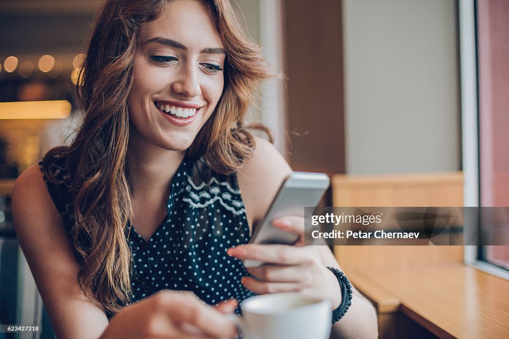 Beautiful girl texting in cafe