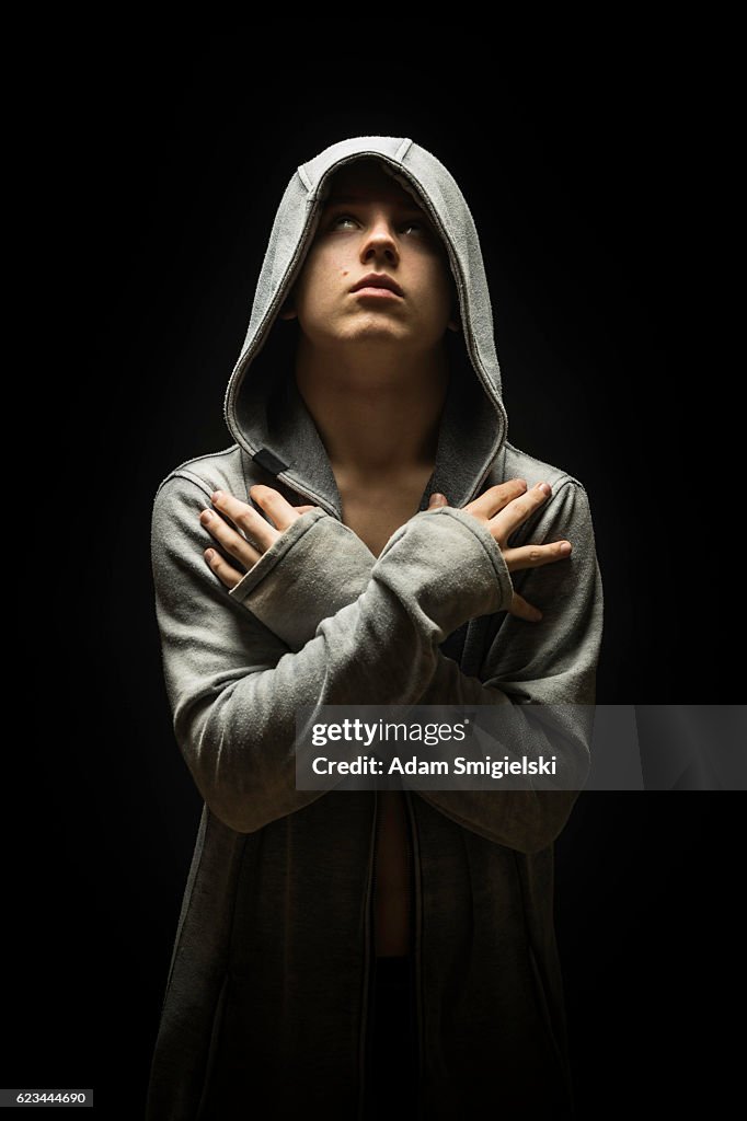 Teenage boy dressed in hooded jacket in the dark