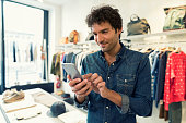 Man texting on cellphone in clothing store